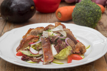 Mix leaves with pork roast slices, crackling, apple, Camembert cheese, cherry tomatoes, and apple vinaigrette
