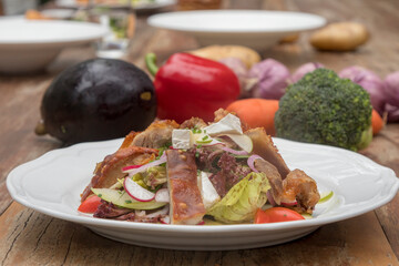 Mix leaves with pork roast slices, crackling, apple, Camembert cheese, cherry tomatoes, and apple vinaigrette