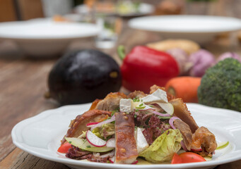 Mix leaves with pork roast slices, crackling, apple, Camembert cheese, cherry tomatoes, and apple vinaigrette