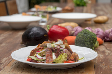 Mix leaves with pork roast slices, crackling, apple, Camembert cheese, cherry tomatoes, and apple vinaigrette