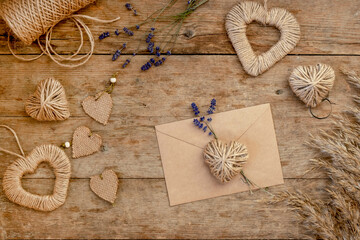 Zero waste Valentine's Day concept and mock up. craft paper envelope, with do it youself decor with lavender, pampas grass and jute hearts. Top down view or flat lay.