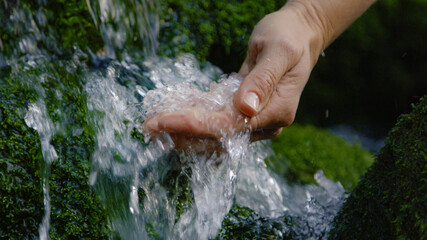 CLOSE UP: Thirsty person uses hand to scoop up a handful of cold stream water. © helivideo