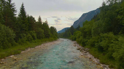 DRONE: Flying low along a turquoise mountain stream coursing through the woods.