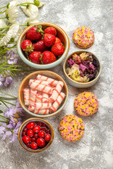 Obraz na płótnie Canvas top view fresh strawberries with candies and cookies on light background biscuit fruit sweet