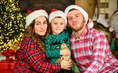 Feast of Christmas. merry christmas. mom dad and small kid have fun on party. happy family celebrate new year. parents with son wear santa hat. father and mother with child stay home on holidays