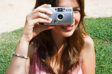 Young woman using an analog film camera  staring at camera