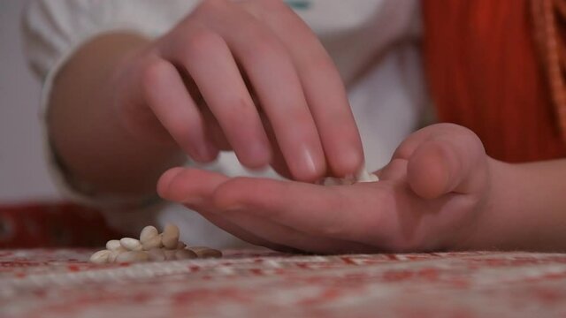 Sorting beans by hand by the hands of a young girl