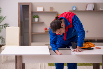 Young male contractor repairing table indoors