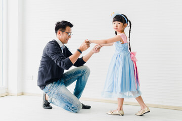 Obraz premium An Asian father and daughter are dancing, dad teaches daughters to dance in a fun room