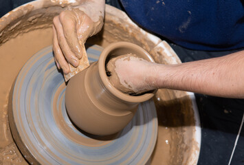 Man hands making ceramic pot vase on the pottery wheel.