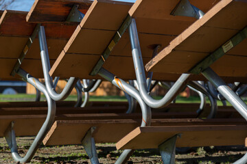 An isolated, close up view of sunlit park picnic benches inter-stacked against each other