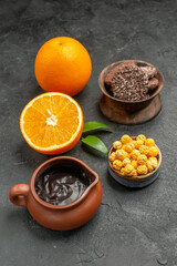 Vertical view of set of whole and cut in half fresh oranges and biscuits on dark background