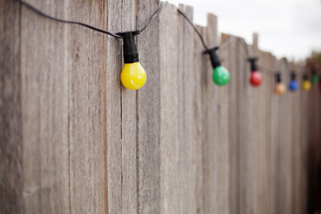 Coloured party lights strung along an old timber fence