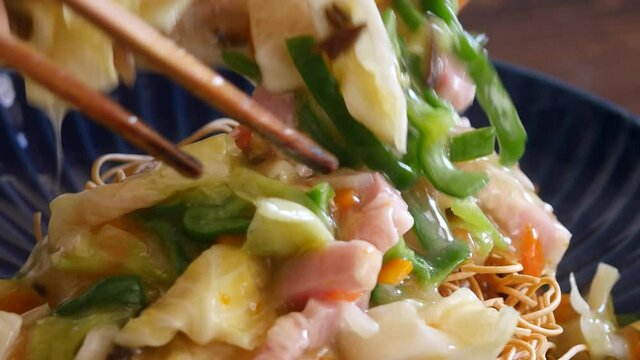 長崎皿うどんのクローズアップ動画。揚げた麺に野菜たっぷりの餡かけをかけて食べる料理。