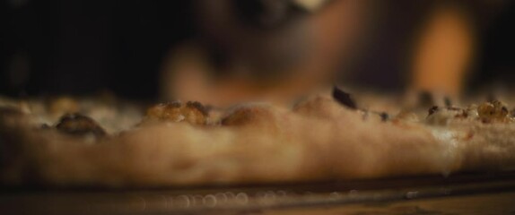 Chef grating parmesan cheese over special al taglio pizza with cauliflower and mushrooms topping.