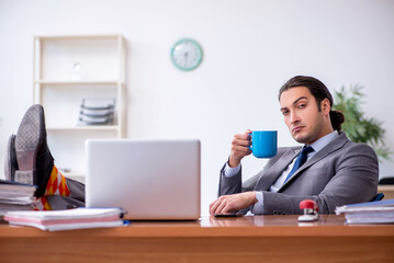 Young male employee drinking coffee in the office