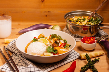 red curry with jasmine rice on a pine table with ingredients spread on the table 