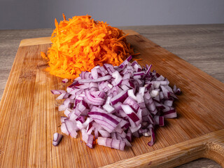 Finely chopped red onions and carrots, lie on a wooden board