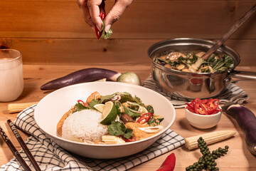 red curry with jasmine rice on a pine table with ingredients spread on the table 