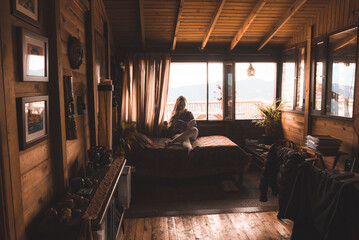 Obraz na płótnie Canvas Peaceful young woman reading a book in a comfortable log cabin resting in a beautiful interior room in bed