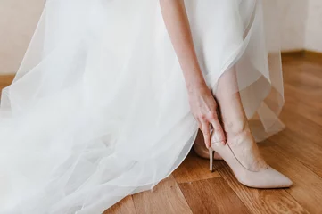 Foto op Plexiglas Bride putting on her stylish classic lacquered beige shoes. Wedding morning preparation in home. © Serhii