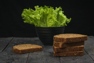 slices of whole-grain bread and lettuce leaves on a wooden table.