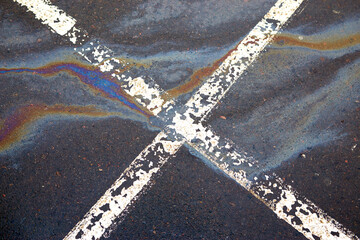 Gas stain on wet asphalt in the car park caused by a leak under a car or truck