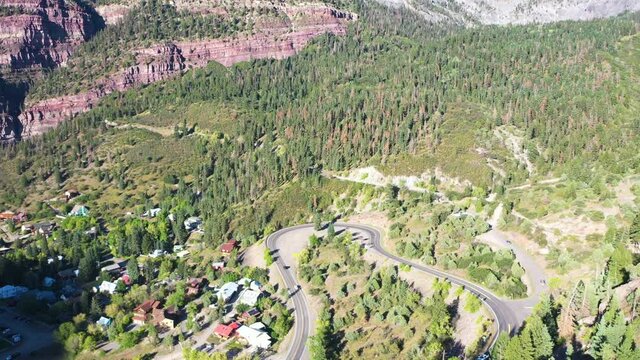 Aerial Drone Lowering Motion of Beautiful Ouray Colorado Pine Tree Forest and Mountain Cliffs with Cars Driving on Highway 550 by Rocky Mountain Houses