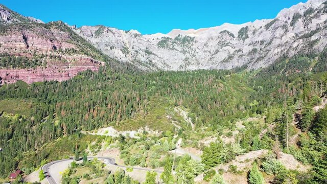 Aerial Drone Footage of Beautiful Ouray Colorado Pine Tree Forest and Mountain Range with Cars Driving on Highway 550 by Rocky Mountain Houses