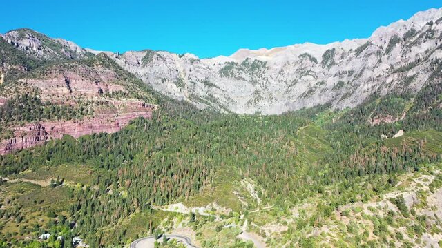 Aerial Drone Fly Over of Beautiful Ouray Colorado Thick Pine Tree Forest and Mountain Peaks During Summer with Cars Driving on Highway 550 by Rocky Mountain Houses