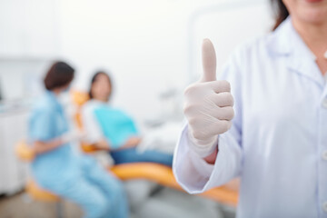 Cropped image of dentist in latex glove showing thumbs up after finishing cavity treatment