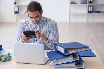 Young male bookkeeper calculating tax payments in the office