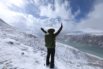 Cheering woman hiker hiking in snowing winter mountains