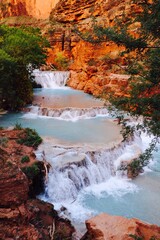 Havasupai falls with multiple blue waterfalls in red canyon and trees