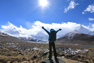 Cheering woman backpacker hiking in winter mountains