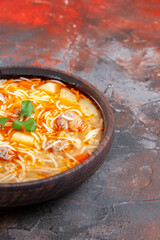 Half shot of delicious noodle soup with chicken in a brown bowl on the dark background