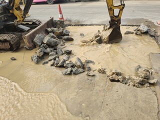 Excavators dig holes to destroy concrete roads to repair damaged water pipes. 