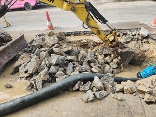 Excavators dig holes to destroy concrete roads to repair damaged water pipes. 