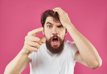An angry man touches his head with his hands on a pink background Copy Space