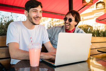 Two young friends using laptop at coffee shop.