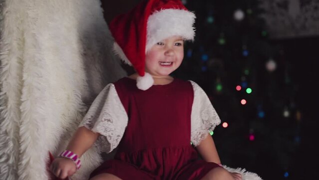 a child in red clothes is sitting waiting for the new year. the concept of celebrating Christmas at midnight. holiday costume. a girl writes a letter to Santa Claus. wish list