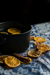 mulled wine in a saucepan is on the table, around lemons, oranges and cinnamon