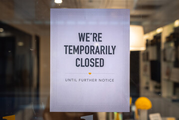 A printed sign is taped to a storefront business in downtown Chicago indicating the business is...