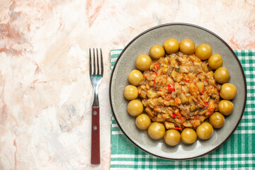 top view roasted eggplant salad and pickled plums on plate on turquoise white checkered tablecloth a fork on nude background