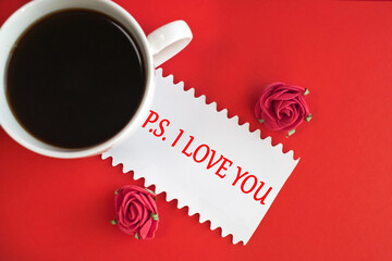 on a red background is a white sheet on which is written the postscript i love you. a white cup of coffee.