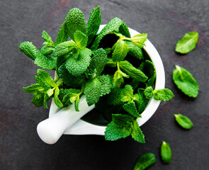 Fresh mint leaves in mortar on stone table. Top view