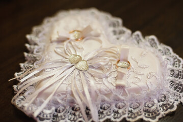 pair of gold wedding traditional rings on a white lace cushion