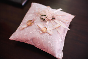 two gold wedding traditional rings on a white cushion