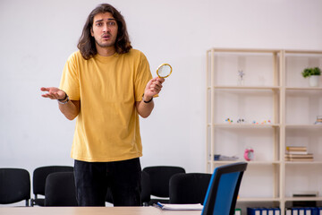 Young male student waiting for teacher in the classroom