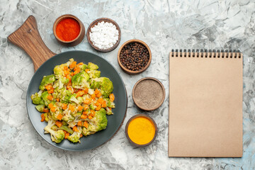 Fresh and healthy vegetable salad on wooden cutting board and notebook on white background